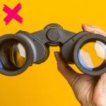 Hand holding a pair of binoculars to represent looking for a healthcare msp.