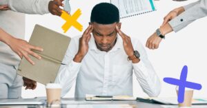 Frustrated man surrounded by hands holding out different tasks for him to represent causes of physician burnout.